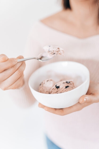 Frau isst entspannt eine Schüssel Eis – Symbol für diätfrei leben und selbstbestimmten Genuss ohne Verbote.